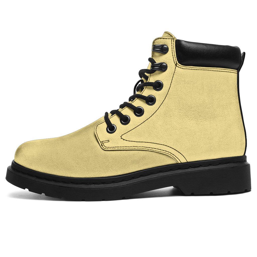 This is a microsuede pair of boots for men and women. It is a light cream colour all over. The boot has a black sole black trim, black laces, and sits above the ankle. It is set on a white background.