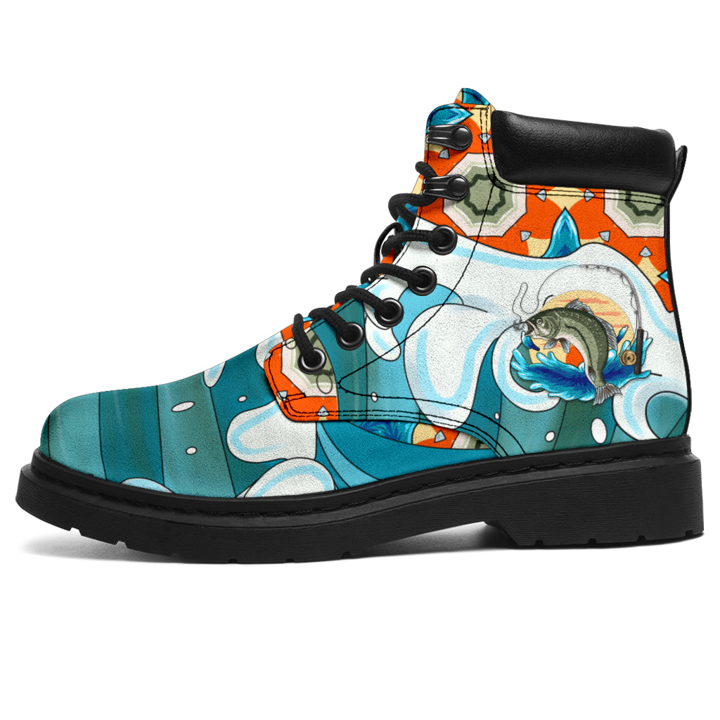 This is a microsuede pair of boots for men and women.  It has a fish surfing on the water with a fishing rod trying to catch the bait, with waves on it. It has orange, blue, aqua and white colours over the boots. The boot has a black sole black trim , black laces, and sits above the ankle. It is set on a white background.