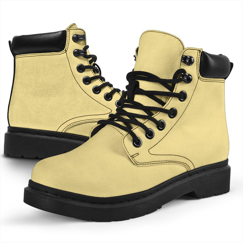 This is a microsuede pair of boots for men and women. It is a light cream colour all over. The boot has a black sole black trim, black laces, and sits above the ankle. It is set on a white background.