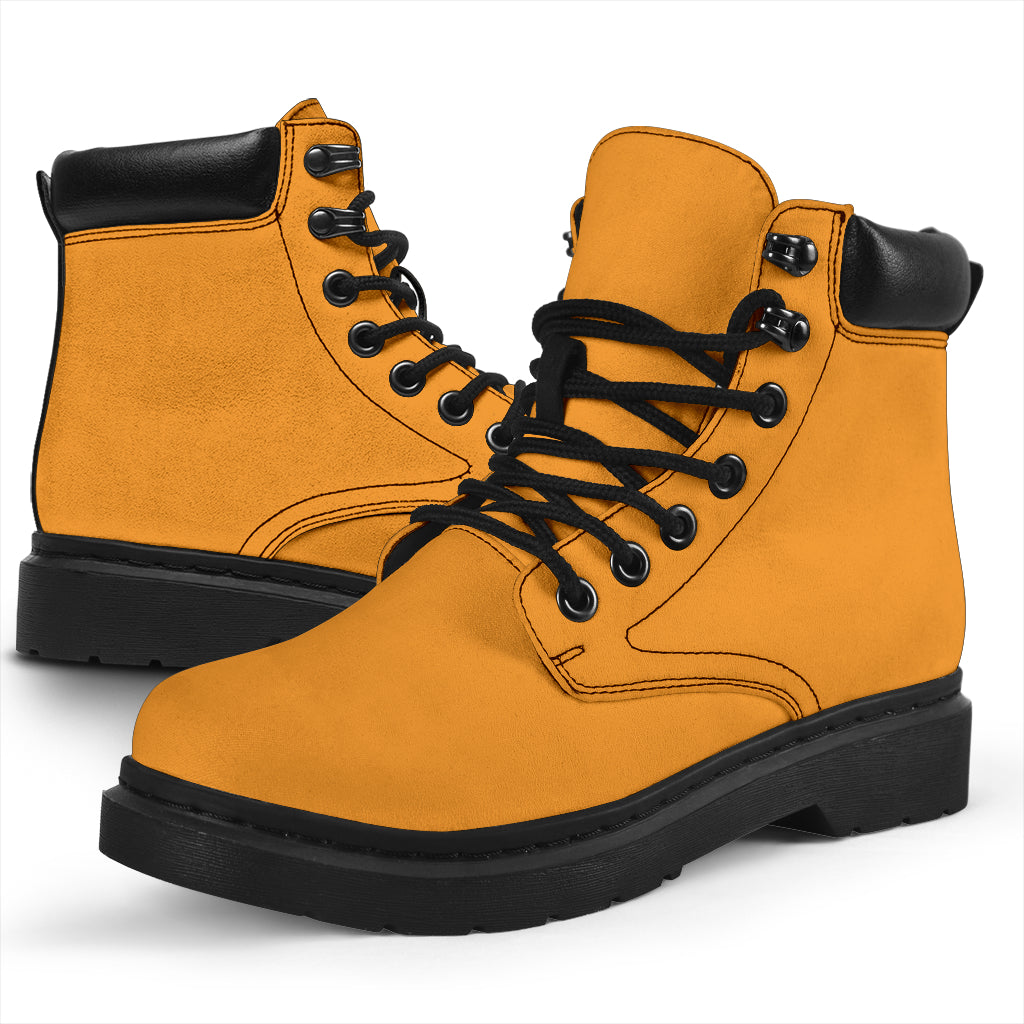 This is a microsuede pair of boots for men and women. It is a mango orange colour all over. The boot has a black sole black trim, black laces, and sits above the ankle. It is set on a white background.