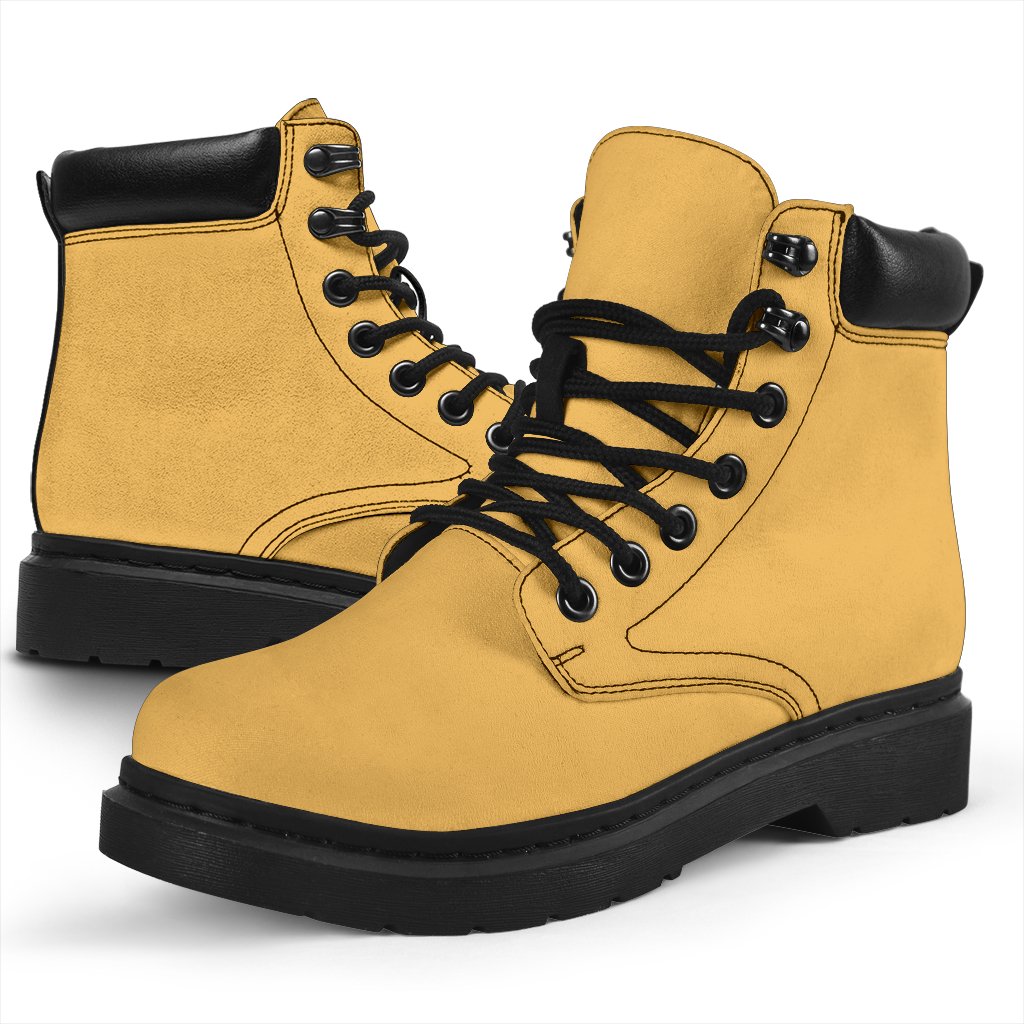 This is a microsuede pair of boots for men and women. It is a dark yellow colour all over. The boot has a black sole black trim, black laces, and sits above the ankle. It is set on a white background.