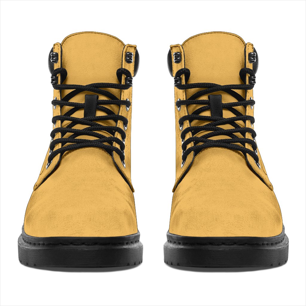 This is a microsuede pair of boots for men and women. It is a dark yellow colour all over. The boot has a black sole black trim, black laces, and sits above the ankle. It is set on a white background.