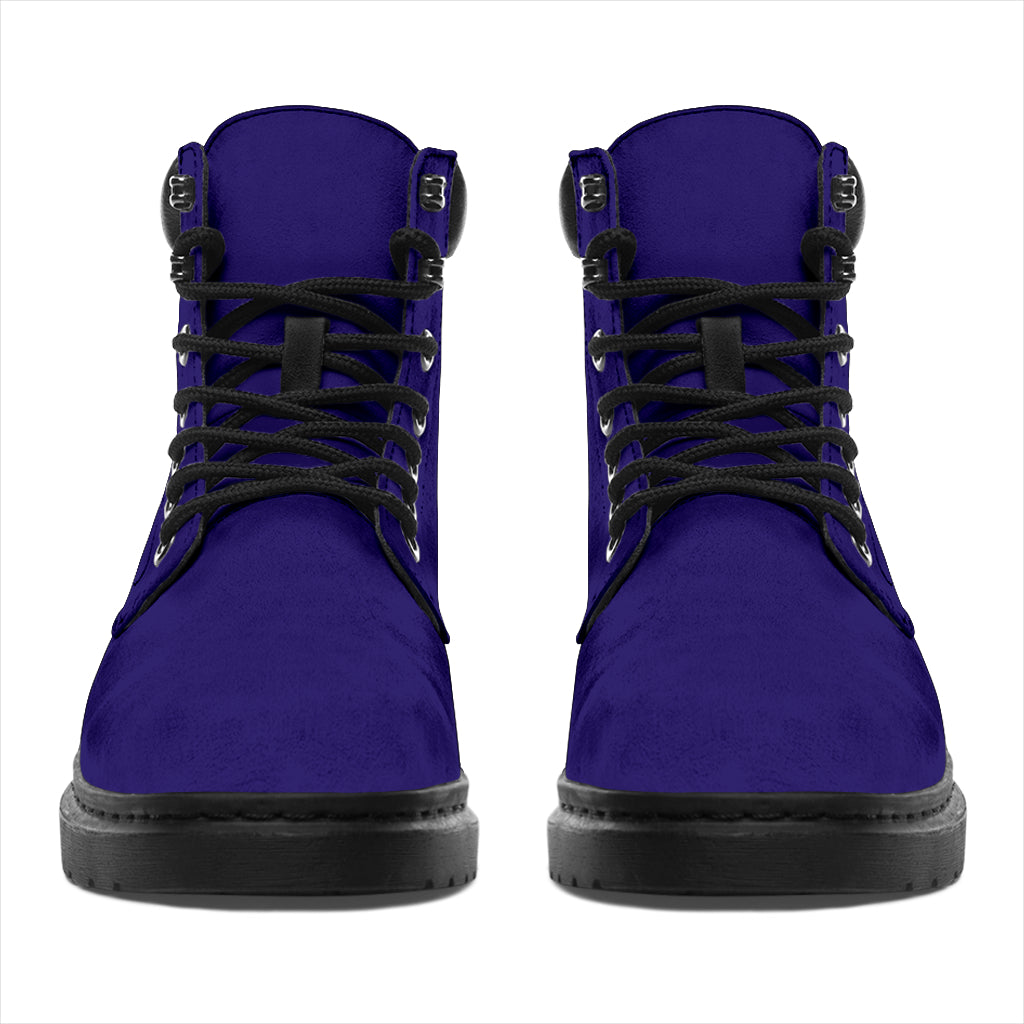 This is a microsuede pair of boots for men and women. It is a dark purple colour all over. The boot has a black sole black trim, black laces, and sits above the ankle. It is set on a white background.