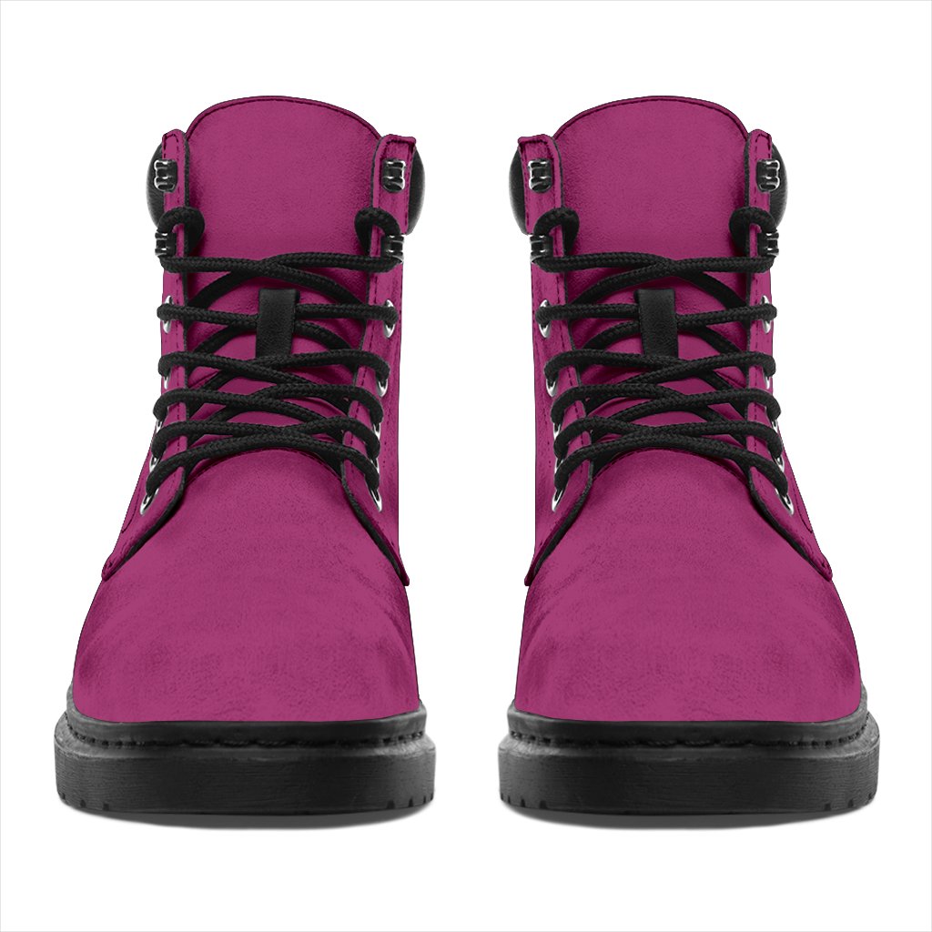 This is a microsuede pair of boots for men and women. It is a magenta pink colour all over. The boot has a black sole black trim, black laces, and sits above the ankle. It is set on a white background.