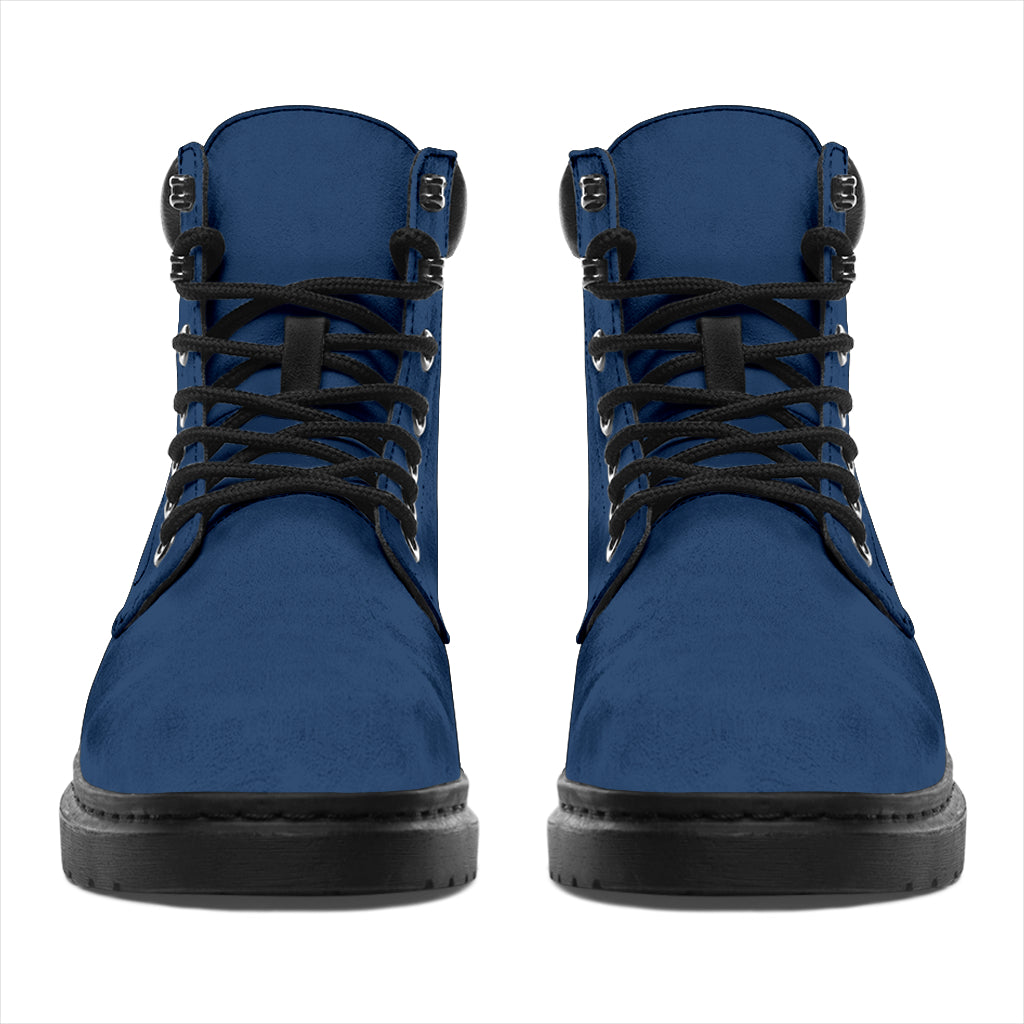 This is a microsuede pair of boots for men and women. It is a ink blue colour all over. The boot has a black sole black trim, black laces, and sits above the ankle. It is set on a white background.