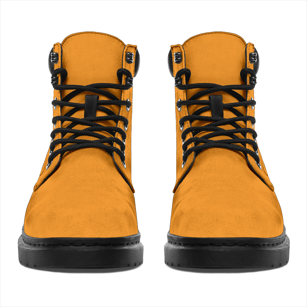 This is a microsuede pair of boots for men and women. It is a mango orange colour all over. The boot has a black sole black trim, black laces, and sits above the ankle. It is set on a white background.